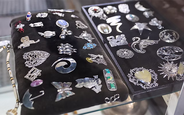 Collection of intricate sterling silver brooches and pins on velvet display pads