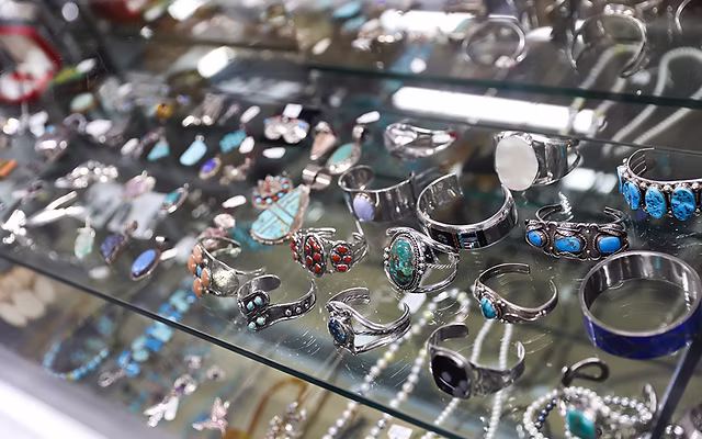 Glass display case filled with vintage sterling silver and turquoise cuff bracelets