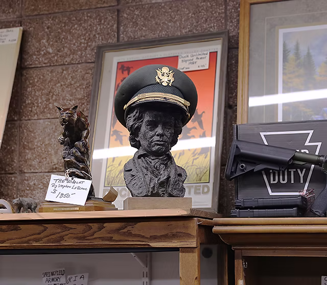 Shelf display featuring a military officer bust, bronze cougar statue, and framed wildlife art